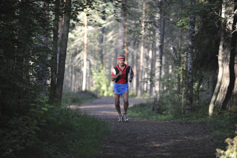 Corredor de más de 60 años en un rodaje suave por un camino forestal