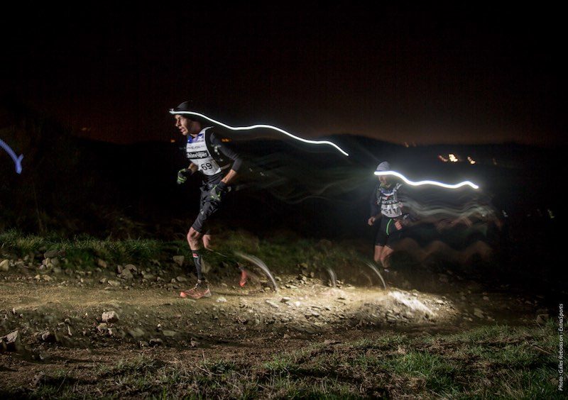 Runner corriendo de noche con luz frontal y chaleco reflectante para ver mejor y ser visible.