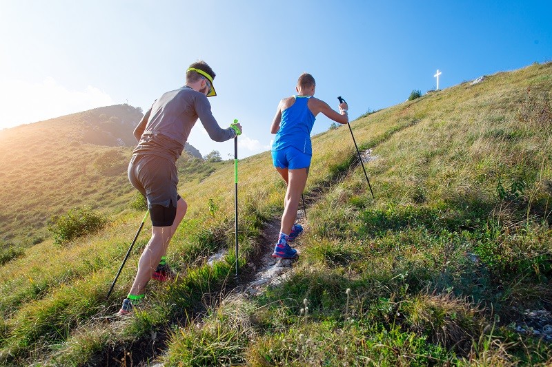 Corredor de trail running usando bastones para subir más rápido y mejorar el rendimiento.