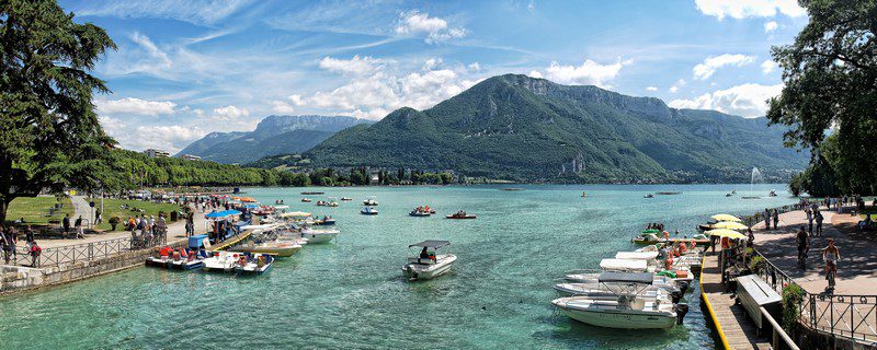 Corredor en ruta de trail running en Annecy con vistas al lago y montañas.