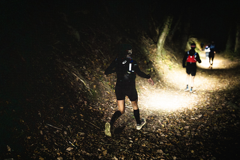 Corredor de trail nocturno se alimenta para mantener energía durante toda la noche en la montaña